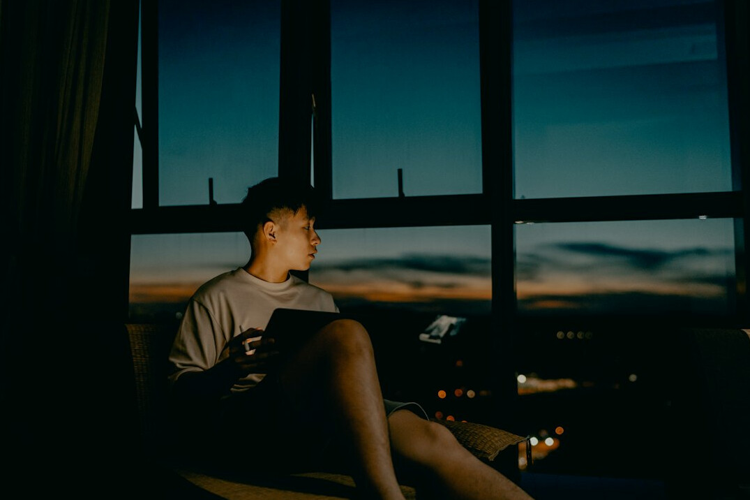 Young man reading a book by a window for personal growth